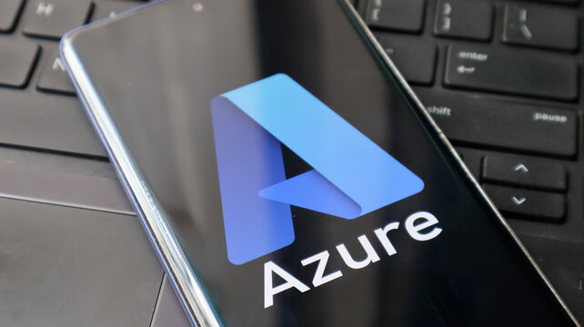 A smartphone displaying the Microsoft Azure logo on its screen next to a laptop keyboard