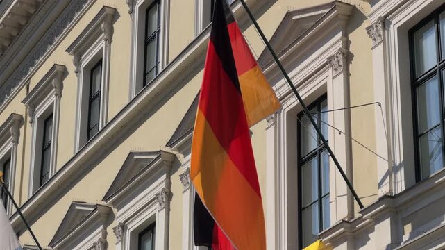 The German flag waving on an administrative building near Odeonsplatz in Munich. Historic architecture in the city center of Bavaria, Germany. Official state symbol.