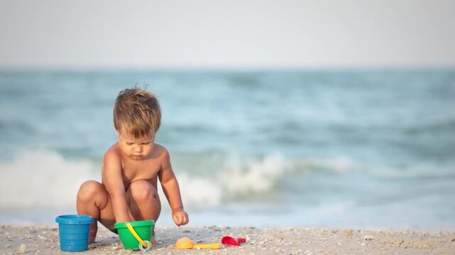 Kid collects shells and pebbles in the sea on a sandy bottom under the summer sun on a vacation