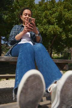 Low angle view of woman using smartphone outdoors against blue sky
