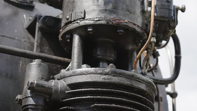 Close up of mechanical steaming details, wheels and piston of a vintage steam engine. Historic locomotive, industrial heritage, 4K, ProRes, 50fps.