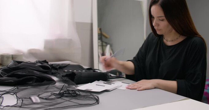 Tailor manager work. Designer accounting. Woman writing order label paper package card at desk. Brand studio clothes product industry.