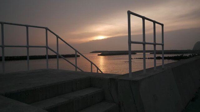 防波堤の階段から見る波けしブロックのある夕日の海