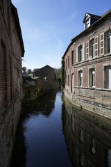 Obraz premium Canal étroit entre de vieilles façades de briques, Guise, Narrow Canal Between Old Brick Facades, Guise