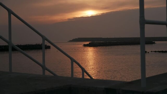 防波堤の階段から見る波けしブロックのある夕日の海
