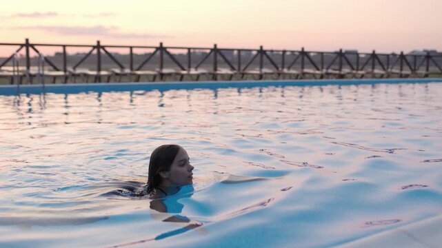Girl in leopard swimsuit playing in the pool under the summer sun