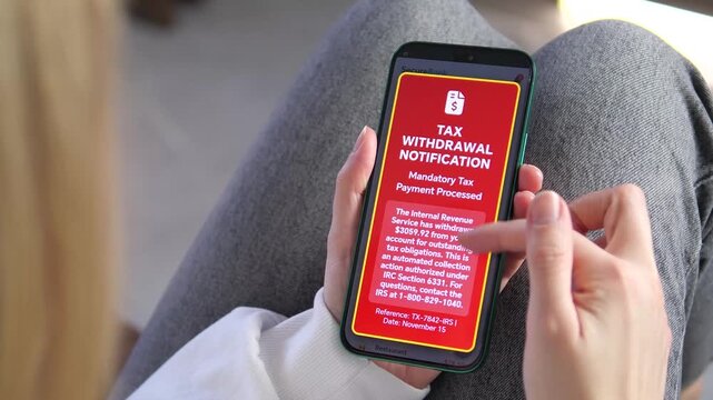 Close-up of a woman checking her bank balance on a smartphone when a red tax withdrawal notification pops up. Perfect for content about IRS audits, mandatory payments, and financial stress