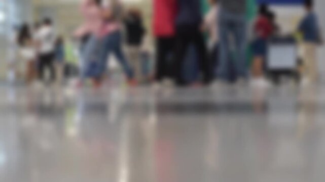 Blurred scene of a busy airport terminal. People, passengers, travelers walking with their luggage. People waiting at the arrival area.