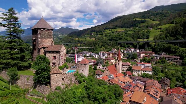 Italy South Tyrol 4k aerial drone panning from historic Branzoll castle to Chiusa Klausen town. Scenic landscape with chapel and vineyards in Isarco valley. Beautiful Alpine village architecture