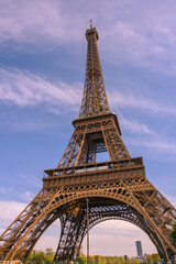 Obraz premium Iconic Eiffel Tower structure against a bright blue sky with wispy clouds