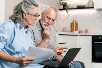 Fototapeta premium Couple reviews budget and utility bills together at home using laptop