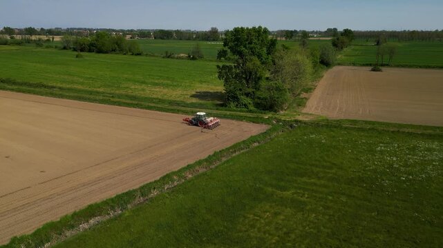 Agricultural Landscape: A wide, serene view from above, as a tractor methodically cultivates a field. An ode to agricultural perseverance.