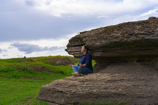 Young woman meditating alone near coastal rock, quiet posture, fresh air, mindful scene linked to focus, clarity, brain health concept