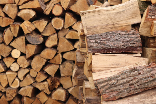Stacked wooden logs. Close-up of stacked firewood. Natural wooden background. Background of chopped firewood ready to use. Suitable for themes related to heating, nature or rural life