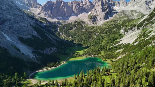 Aerial drone view of the Alps and the green Seebensee on a sunny summer day. A couple enjoys the view of Seebensee and goes hiking. Seebenlake	
