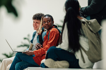 Obraz premium Group of diverse university students studying together on campus, connecting and sharing laptop during break time