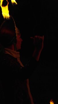 Mystical fire dancer performing with glowing flames against a dark night background, creating dynamic light trails and dramatic shadows in an atmospheric scene