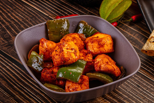 Indian Paneer Tikka Masala inl with Roti bread on a dark wooden table