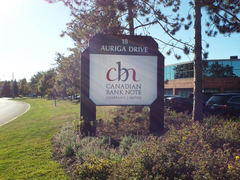 Ottawa, Ontario, Canada &ndash; July 27, 2025: A "Canadian Bank Note Company" sign stands at 18 Auriga Drive in Ottawa, surrounded by garden plants and autumn trees.