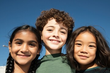Fototapeta premium Three children grouped together under bright blue sky