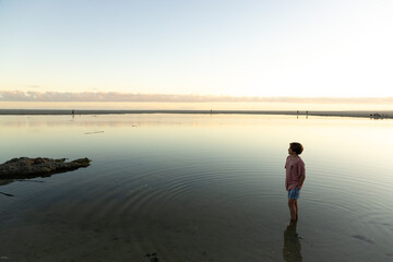 Fototapeta premium boy wading into lagoon at sunset, Hermanus, South Africa