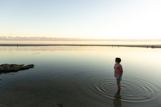 boy wading into lagoon at sunset, Hermanus, South Africa