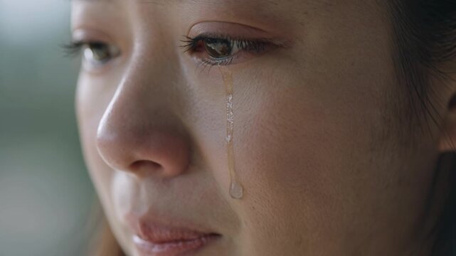 Extreme Close-up of a Sad Young Woman Crying with a Single Tear Rolling Down Her Cheek