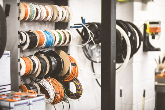 Various spools of colorful electrical wire and cables neatly organized on a rack