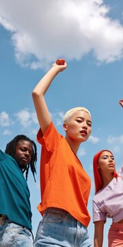 Young adults reaching upward under cloudy blue sky