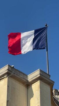 Azure sky hosts flag fluttering beside ancient stone structure