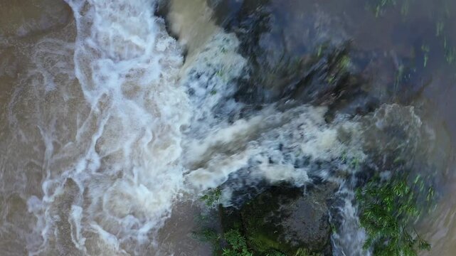 Clear water that runs over rocks and turning in a brown turbulent stream with foam on top