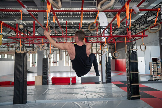 An athletic man practices at a ninja club's indoor obstacle course.