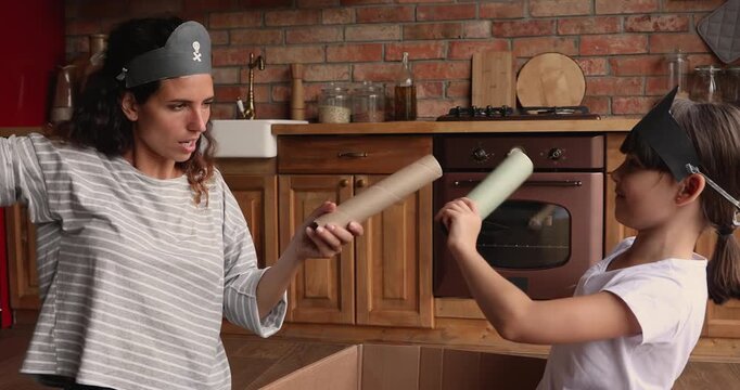 Mother playing imaginary pirate game with daughter at home, family having fun, enjoying playtime in domestic kitchen. Parent and child bonding, and creative childhood leisure indoor activity concept