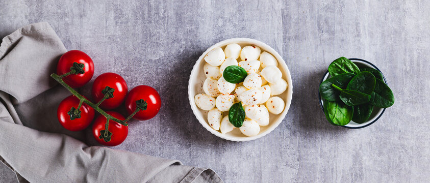 A bowl of mozzarella balls and spinach on the table top view web banner