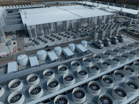 Aerial view of a large AI data center featuring extensive cooling fans, storage tanks, and industrial systems supporting high-performance computing infrastructure.