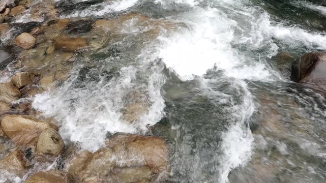 Moving closely over a quick current in a mountain stream with blue water and white foam around the many pebbles