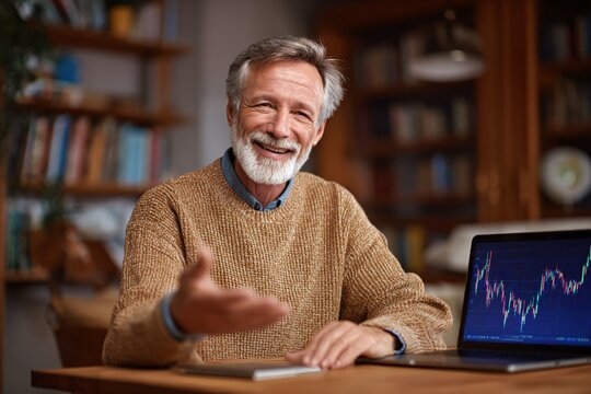 Cheerful Senior Man in Sweater Working on Laptop at Home Office Smiling