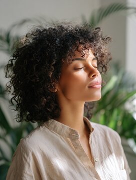 Serene Young Woman Enjoying Sunlight Indoors Amongst Greenery with Eyes Closed
