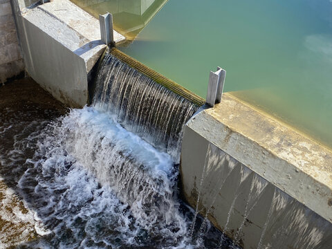 Flashboard Dam, overflow weir. Water flows under bridge through stepped spillway. Water level control structure or Stop log structure
