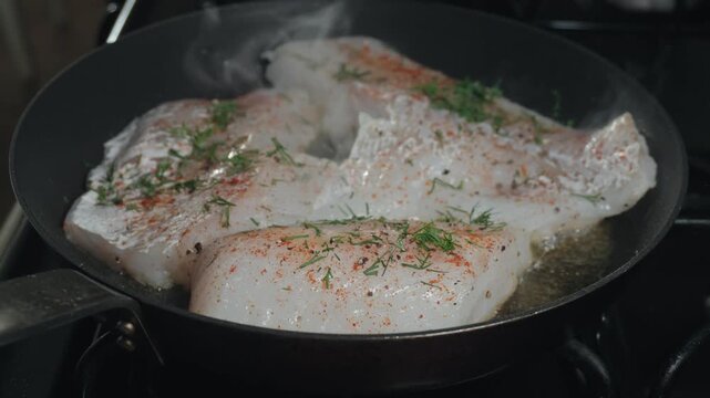 Seasoning white fish with fresh dill in a skillet