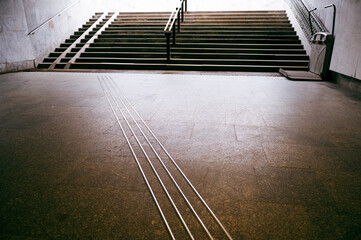Fototapeta premium Tactile ground signs and guide strips assist navigation in a modern city infrastructure for all users at a busy stairway located in a public transport area