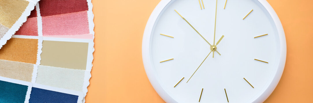 Creative project management concept with color swatches and wall clock on orange background