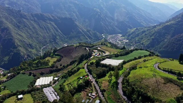Aerial view of agricultural fields and greenhouses build on the mountain hills of the Andes next to Banos de Agua Santa in Ecuador, South America