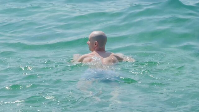 young man swims in sea, ocean, aquatic adventure, man immersed in seawater feels rush of waves filling his ears, risks and dangers swimming in open water, drowning hazard, ear infection