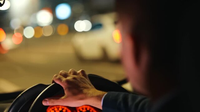 Young man driving car in the city at night. Close up. Right hand drive car. Traveling, trip, night life concept. Real time