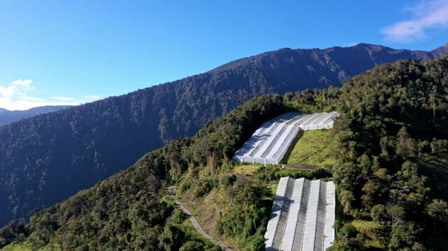 Aerial view of several greenhouses made of white Plastic Polyethylene Covering located on a mountain hill