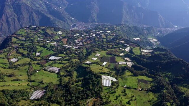 Aerial view over a beautiful valley in the Andean mountains of Ecuador full with greenhouses, meadows and agriculture fields