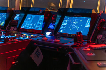 Ship bridge navigation screens with city lights through windows at night © DMITRII RYBALKA