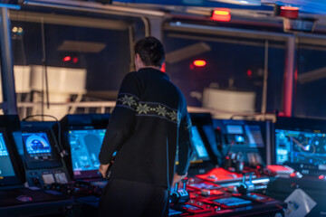 Ship officer standing at bridge navigation console at night © DMITRII RYBALKA