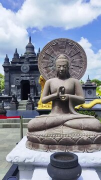 Serene Stone Buddha Statue with Dharma Wheel in Front of Ancient Temple Under Blue Sky
